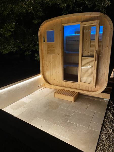 Installation d'un sauna Gaïa Nova extérieur traditionnel avec une douche solaire Jolly Go pour un havre de paix tout confort à La Bastide des Jourdans dans le 84